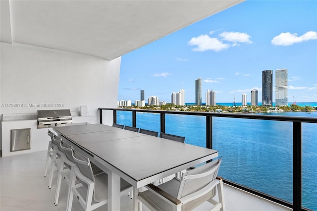 balcony featuring a grill, an outdoor kitchen, a water view, and a bar