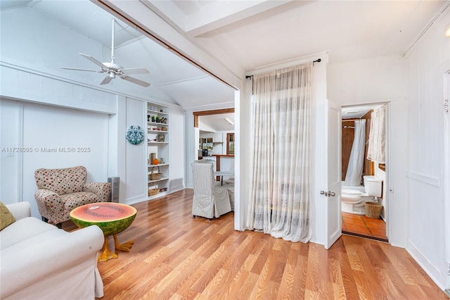 sitting room with ceiling fan, lofted ceiling, light hardwood / wood-style floors, and built in shelves