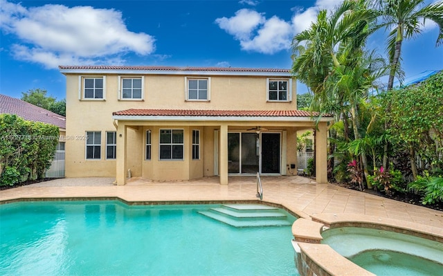 rear view of house with ceiling fan, a patio area, and a swimming pool with hot tub