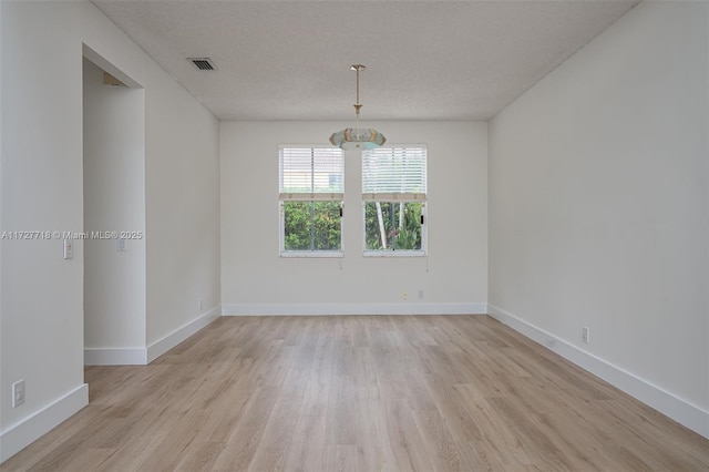 unfurnished room with a textured ceiling and light hardwood / wood-style flooring