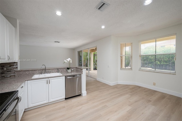 kitchen with a textured ceiling, white cabinets, appliances with stainless steel finishes, light hardwood / wood-style floors, and sink