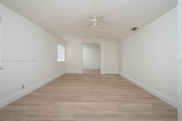 unfurnished room featuring a textured ceiling, ceiling fan, lofted ceiling, and light wood-type flooring