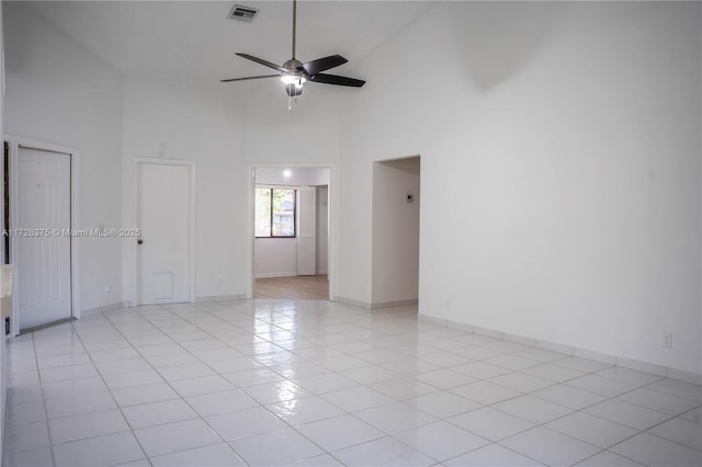 empty room with ceiling fan, light tile patterned flooring, and a high ceiling