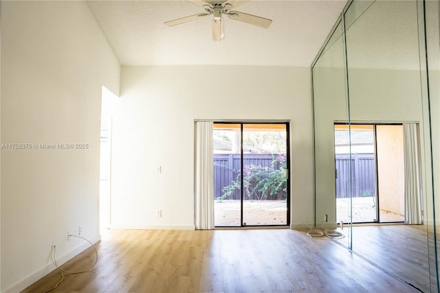 spare room with ceiling fan, light hardwood / wood-style floors, a textured ceiling, and a towering ceiling