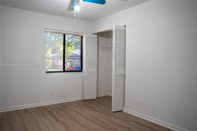 unfurnished bedroom featuring ceiling fan, a closet, light wood-type flooring, and a textured ceiling