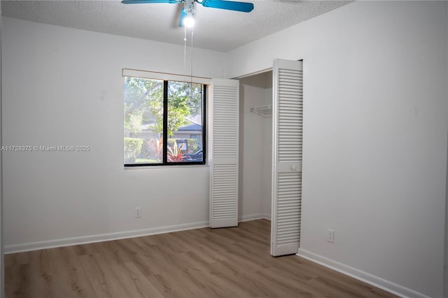 unfurnished bedroom with ceiling fan, a closet, light wood-type flooring, and a textured ceiling