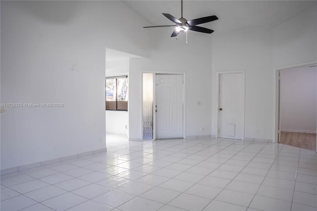 empty room with ceiling fan, light tile patterned floors, and high vaulted ceiling