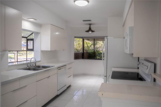 kitchen with light tile patterned flooring, white cabinetry, sink, and white appliances