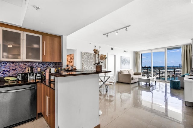 kitchen featuring floor to ceiling windows, stainless steel dishwasher, kitchen peninsula, decorative backsplash, and light tile patterned floors