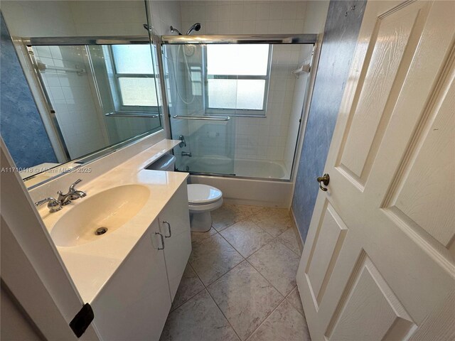 full bathroom with toilet, bath / shower combo with glass door, tile patterned flooring, and vanity