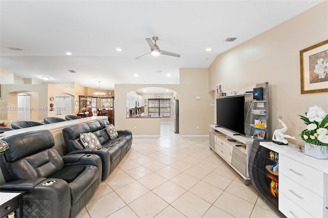 tiled living room with ceiling fan with notable chandelier and lofted ceiling