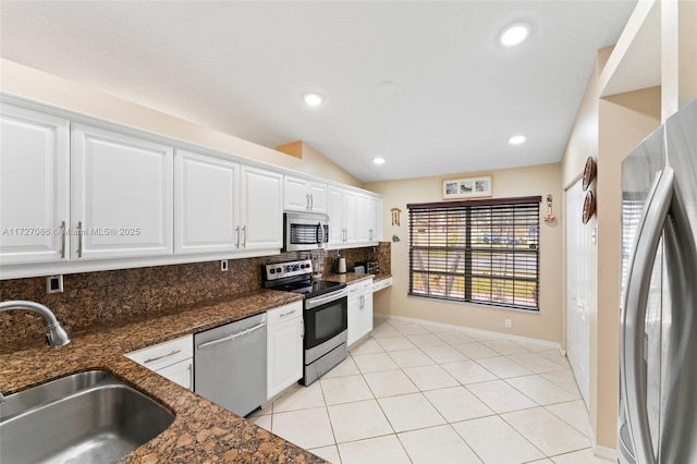 kitchen featuring appliances with stainless steel finishes, white cabinetry, dark stone counters, tasteful backsplash, and sink