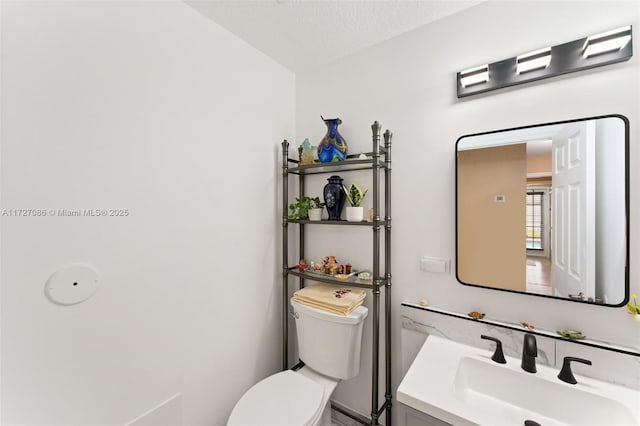 bathroom with toilet, vanity, and a textured ceiling