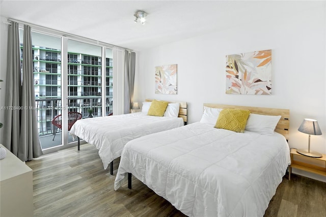 bedroom featuring multiple windows, hardwood / wood-style flooring, and a wall of windows