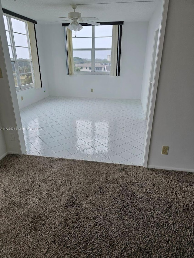 unfurnished room with light tile patterned flooring, ceiling fan, and a wealth of natural light