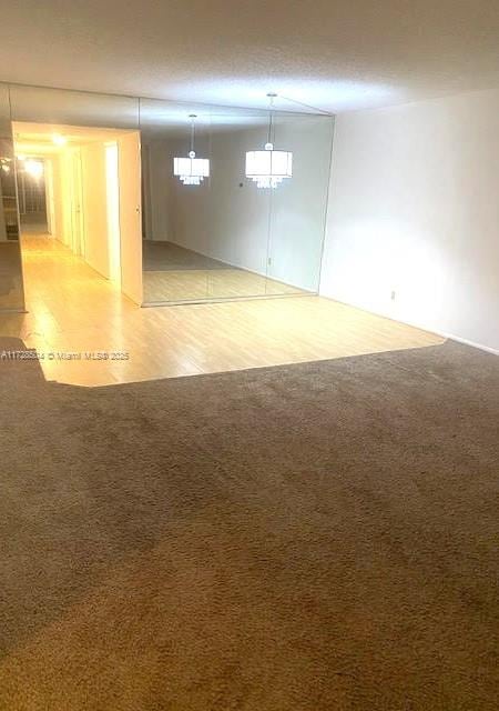 unfurnished room with light colored carpet and an inviting chandelier