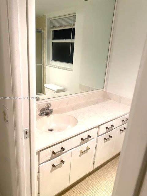 bathroom with a shower with shower door and vanity