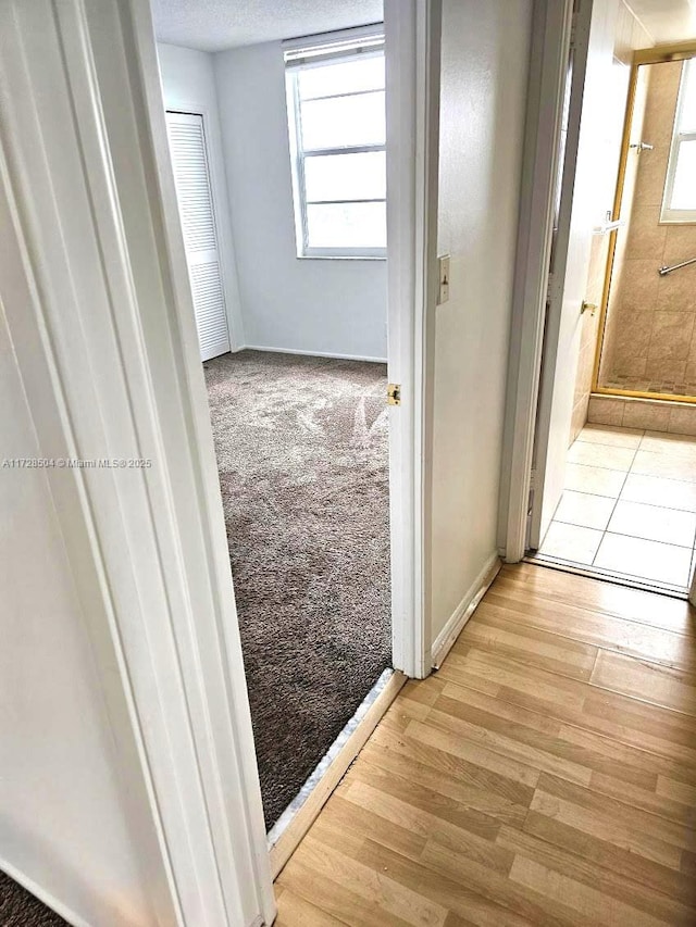 hallway with a textured ceiling and light wood-type flooring