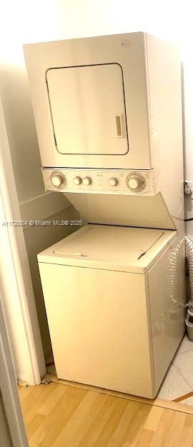 washroom with stacked washer / drying machine and light hardwood / wood-style floors