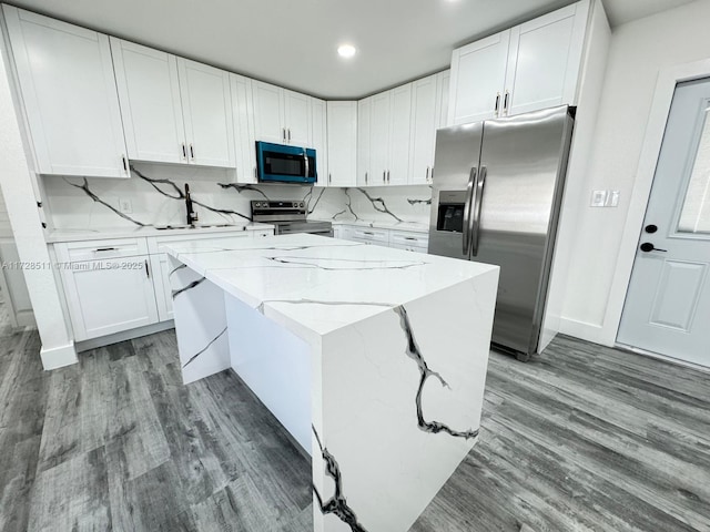 kitchen with appliances with stainless steel finishes, sink, white cabinetry, and a center island