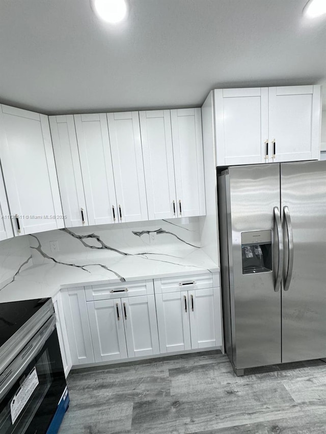 kitchen featuring appliances with stainless steel finishes, white cabinets, and light stone counters