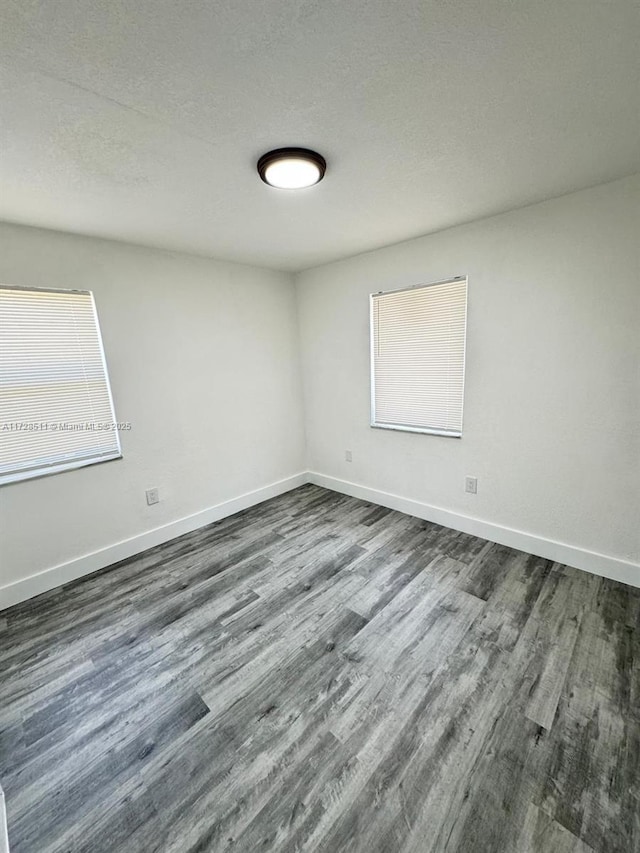 empty room featuring a textured ceiling and dark hardwood / wood-style flooring