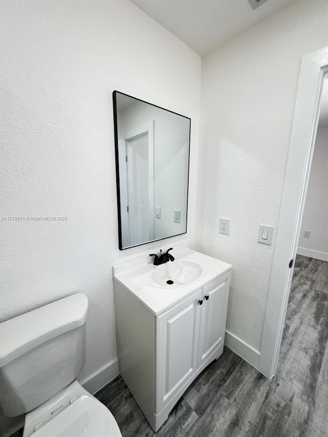 bathroom with toilet, hardwood / wood-style flooring, and vanity