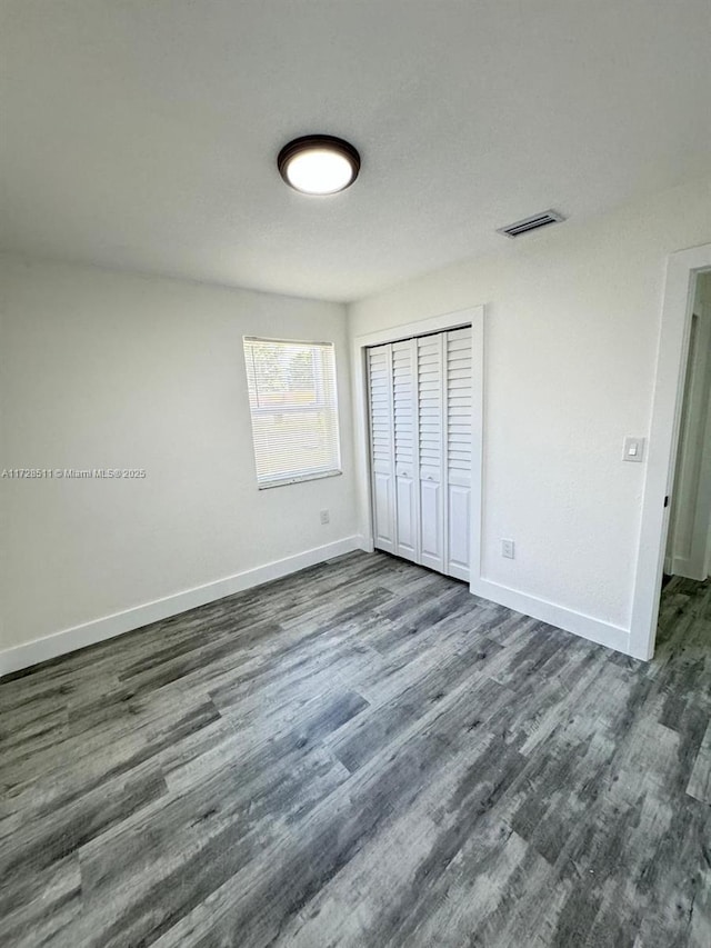 unfurnished bedroom featuring a closet and dark hardwood / wood-style flooring