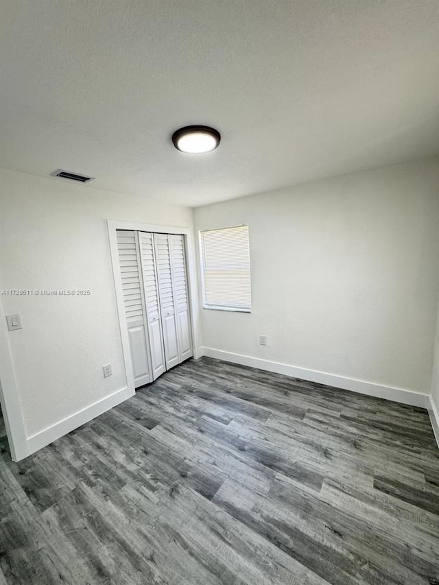 unfurnished bedroom featuring a closet, dark hardwood / wood-style flooring, and a textured ceiling