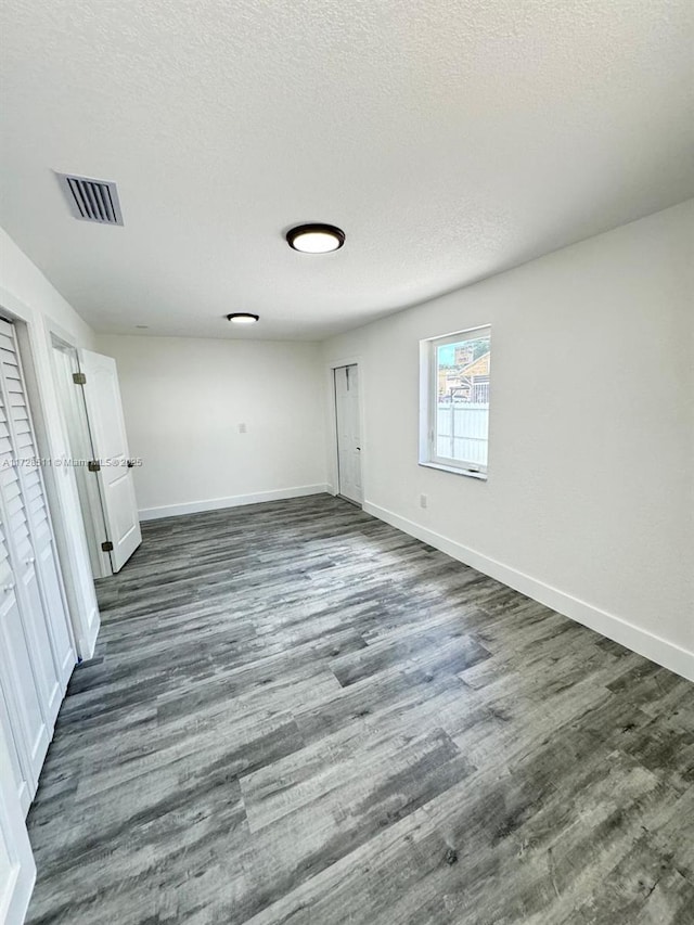 unfurnished room with a textured ceiling and dark hardwood / wood-style flooring