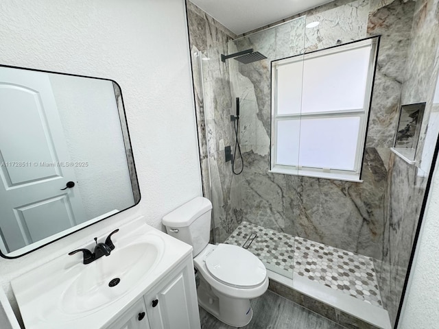 bathroom with toilet, tiled shower, wood-type flooring, and vanity