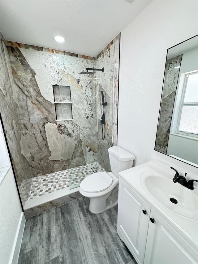 bathroom featuring toilet, vanity, and tiled shower