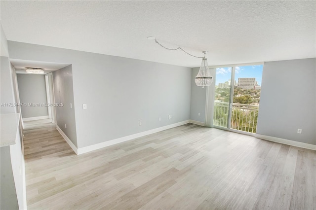 unfurnished room featuring expansive windows, a textured ceiling, and light hardwood / wood-style flooring