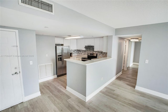 kitchen with tasteful backsplash, light hardwood / wood-style floors, kitchen peninsula, stainless steel appliances, and white cabinets