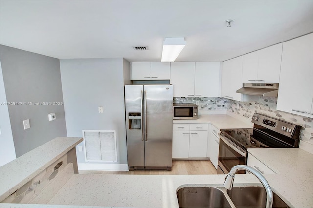 kitchen featuring white cabinets, backsplash, appliances with stainless steel finishes, and sink