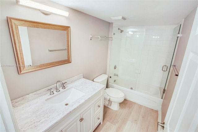 full bathroom featuring toilet, enclosed tub / shower combo, wood-type flooring, and vanity