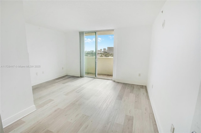 empty room featuring floor to ceiling windows and light hardwood / wood-style flooring