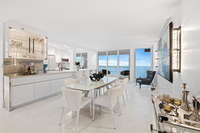 dining space featuring a water view, a wall of windows, and sink