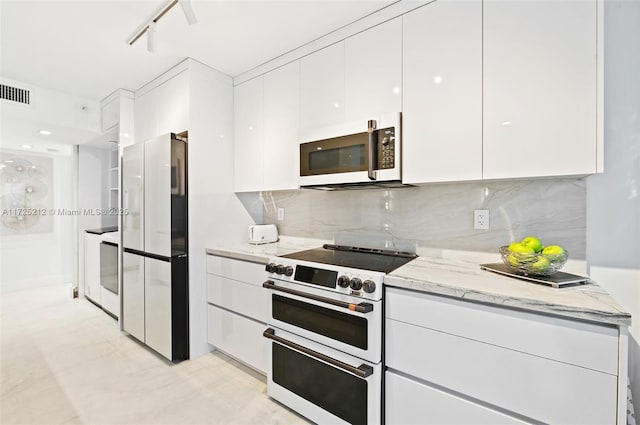 kitchen with double oven range, track lighting, light stone countertops, refrigerator, and white cabinets