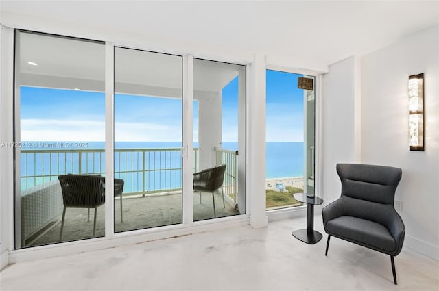 sitting room featuring a view of the beach, concrete floors, and a water view