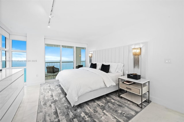 bedroom featuring a water view, access to exterior, and rail lighting