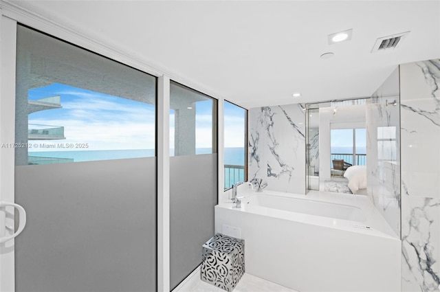 bathroom with a wealth of natural light, a water view, and a tub