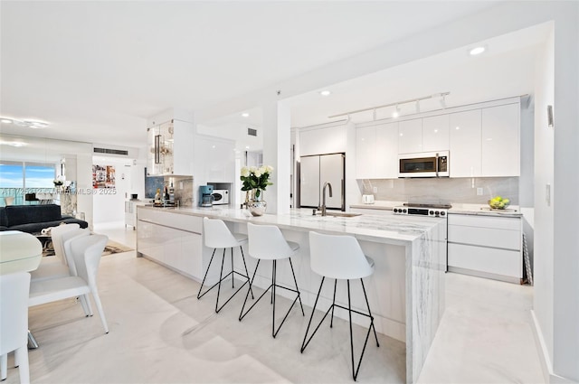 kitchen featuring white fridge, backsplash, a kitchen breakfast bar, white cabinets, and sink