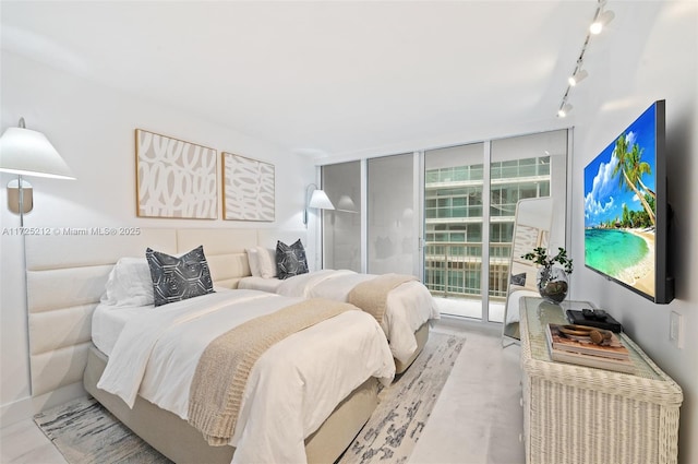 bedroom with access to exterior, expansive windows, and rail lighting