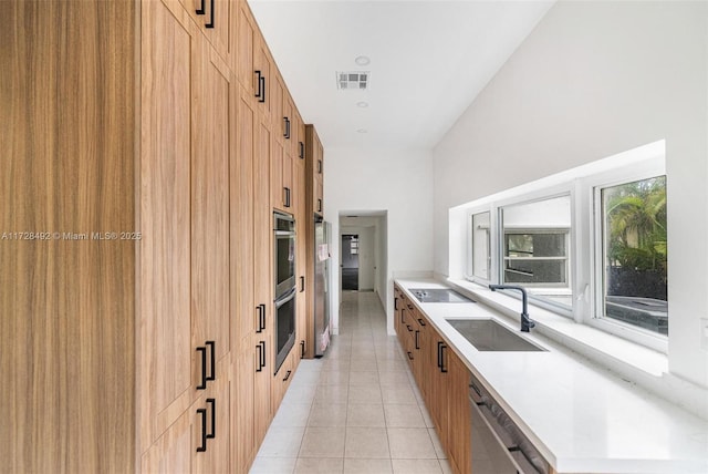 kitchen with sink, light tile patterned floors, and black appliances