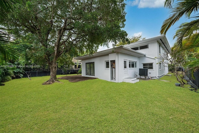 rear view of house featuring a lawn and cooling unit