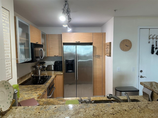 kitchen with light stone countertops, sink, pendant lighting, and black appliances