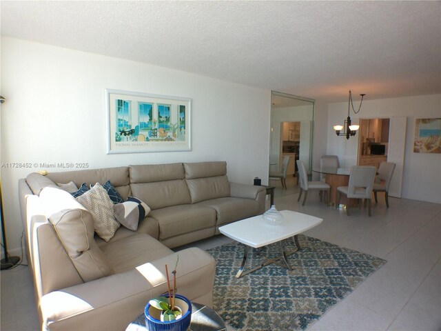 living room featuring a notable chandelier, light tile patterned floors, and a textured ceiling