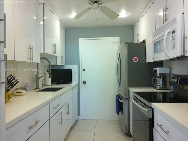 kitchen featuring light tile patterned floors, white appliances, sink, ceiling fan, and white cabinetry