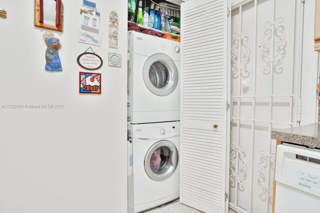 laundry room featuring light tile patterned floors and stacked washer / drying machine